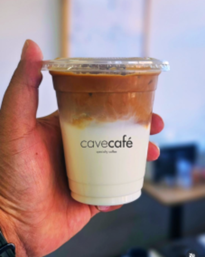 Our signature iced Spanish latte, held up outside the café